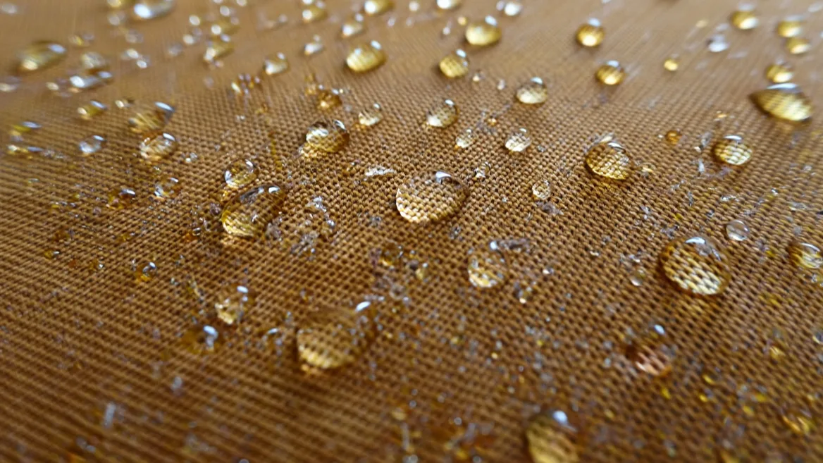Gouttes d'eau perlant sur un tissu imperméabilisé