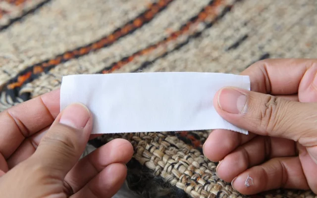 Nettoyage délicat d'un tapis en laine tissée avec un chiffon blanc